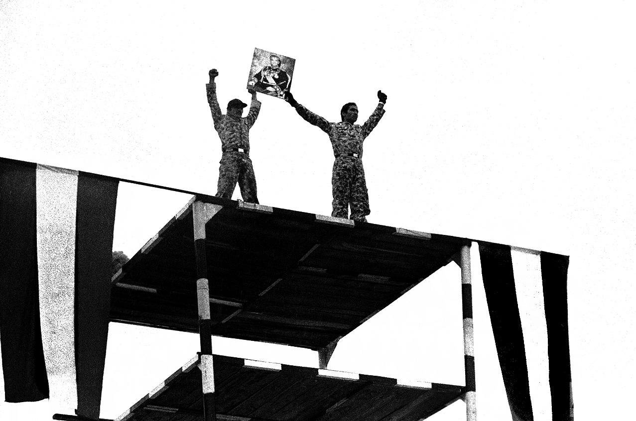 23 января 1979 года. Двое иранских солдат держат портрет шаха, армия демонстрирует свою силу в Тегеране на плацу возле дворца Ниаваран. Офицеры заверили, что армия останется единой и что солдаты «прольют свою кровь», чтобы сохранить монархию и гражданское правительство страны